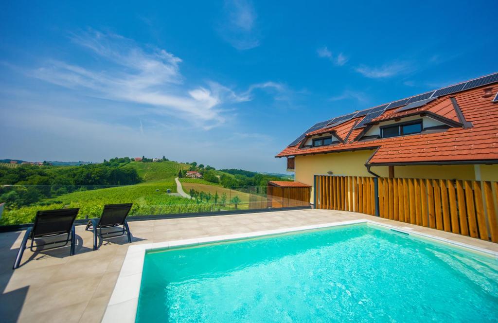 a swimming pool with two chairs and a house at Turistična Kmetija Puklavec in Zasavci