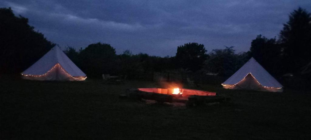 un grupo de tres tiendas de campaña en un campo por la noche en Brackenside Glamping, en Woodhall Spa