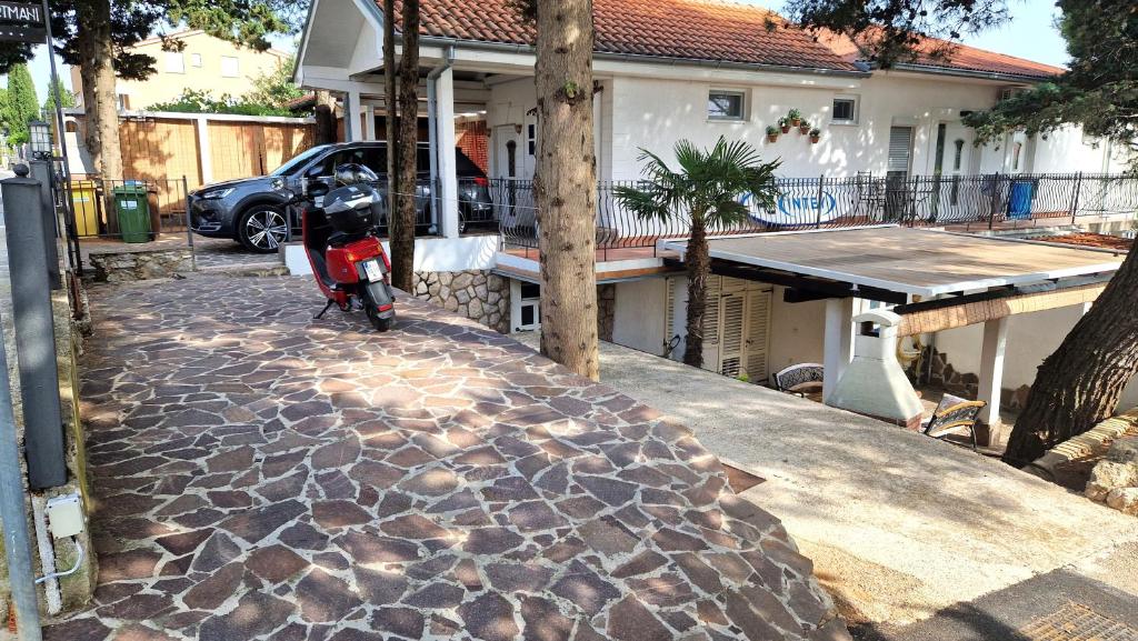 ein Roller, der auf einem steinernen Gehweg vor einem Haus parkt in der Unterkunft Apartment Damijan in Krk