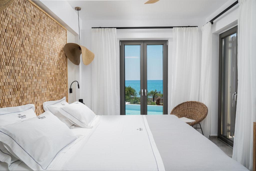 a bedroom with a bed and a view of the ocean at Mnḗmē Suites & Villas in Kastrí