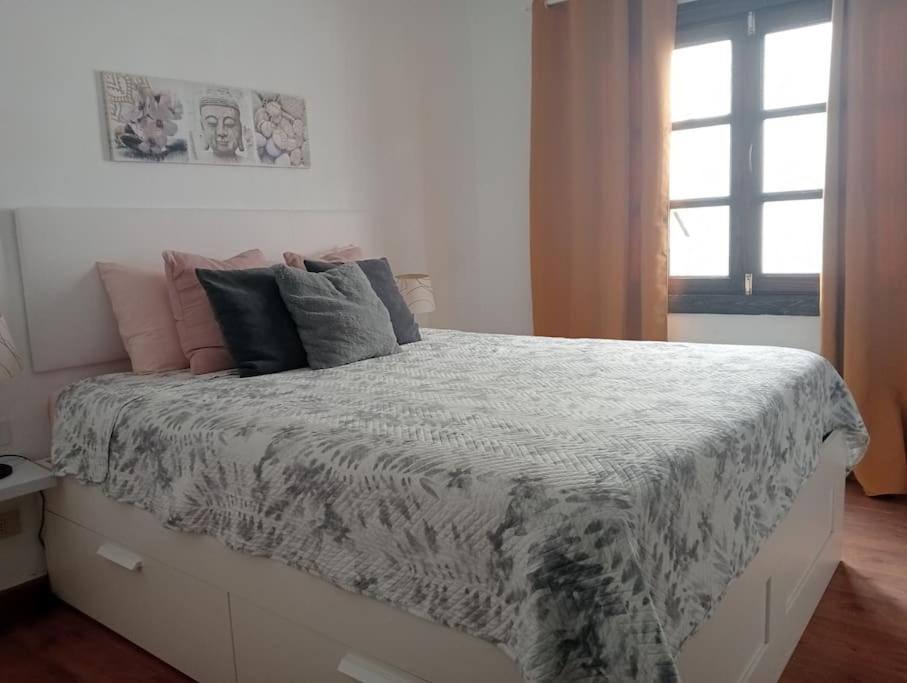 Un dormitorio con una gran cama blanca con almohadas. en Sol y terraza, en Playa Honda