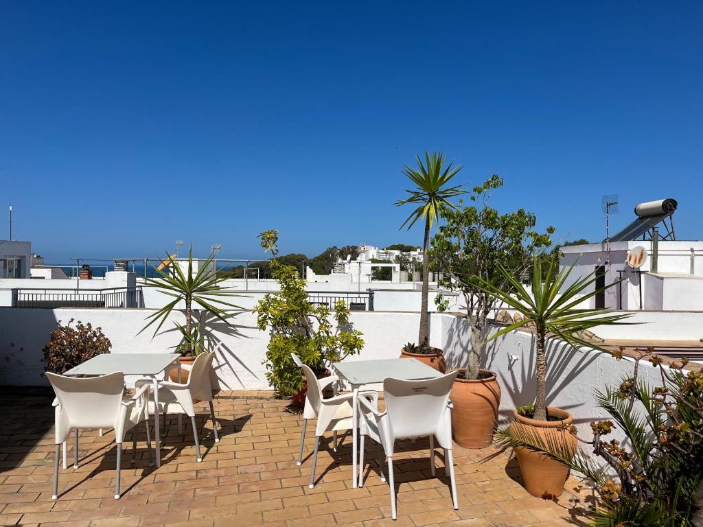 a patio with white tables and chairs and plants at Hostel Conil in Conil de la Frontera