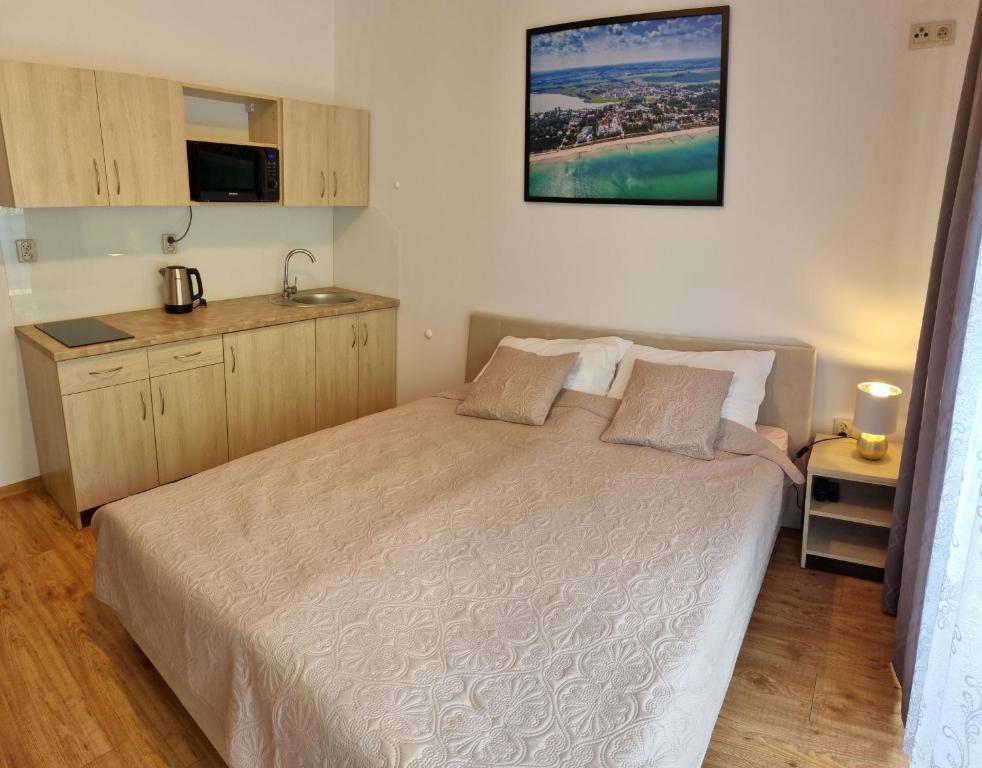 a small bedroom with a bed and a kitchen at Pogodna 3B in Mielno