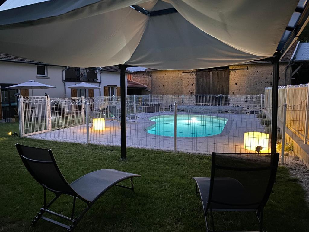 a tent with two chairs and a swimming pool at le clos des flâneries 