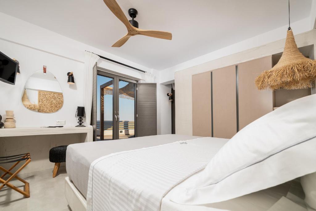 a white bedroom with a bed and a desk at Mnḗmē Suites & Villas in Kastrí