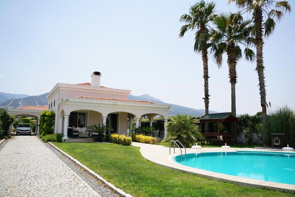 a house with a swimming pool and palm trees at Luxury Villa Narlıdere in Narlıdere