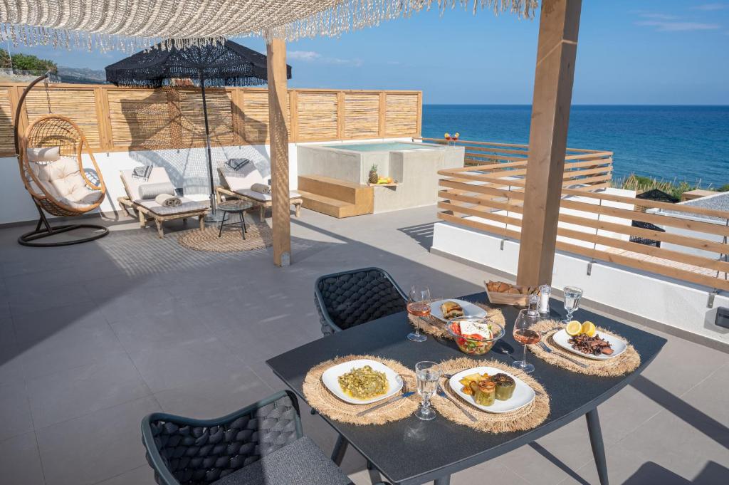 a table with plates of food on a patio with the ocean at Mnḗmē Suites & Villas in Kastrí