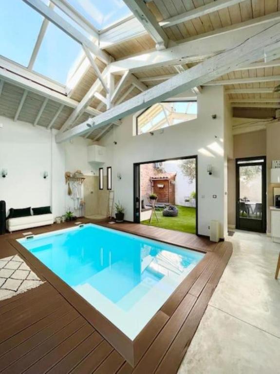 une grande piscine dans une maison avec un plafond dans l'établissement La Nomade - Maison contemporaine avec piscine - Toulouse, à Toulouse