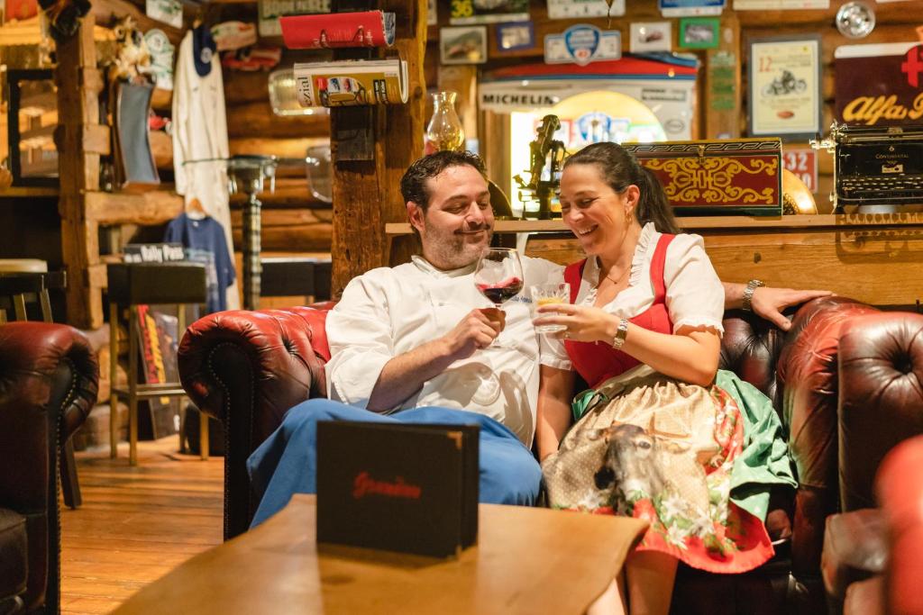 a man and a woman sitting in a chair drinking wine at Boutiquethotel Grandau in Sankt Gallenkirch