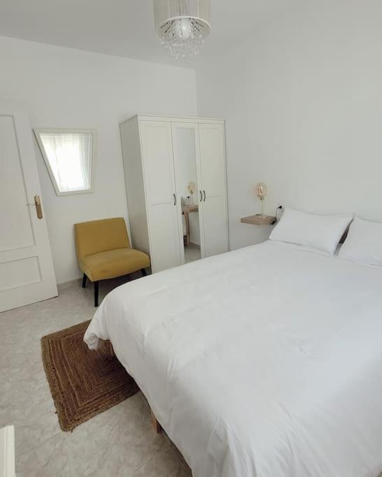 une chambre avec un grand lit blanc et une chaise dans l'établissement Casa Tonino: Encantadora casa junto al Río Duero, à Zamora
