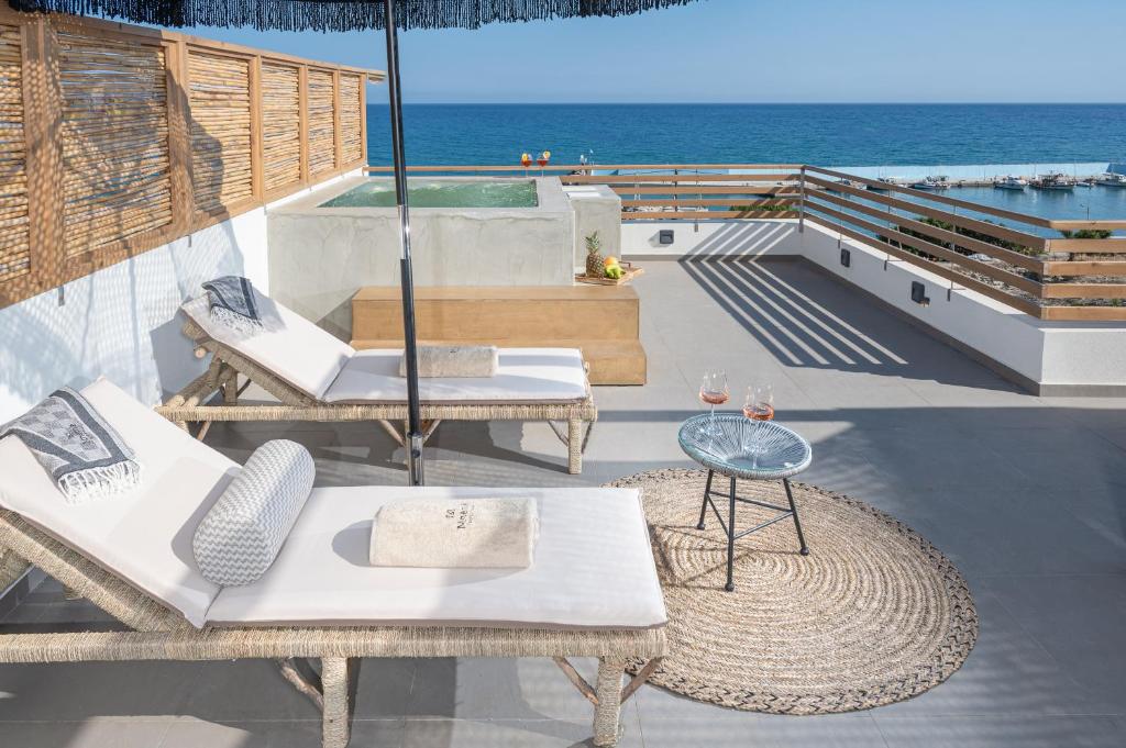 a patio with chairs and a table and the ocean at Mnḗmē Suites & Villas in Kastrí