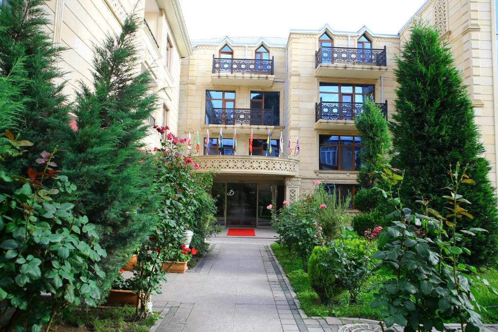 un edificio con árboles y plantas delante de él en Deluxe Hotel Ganja, en Ganja