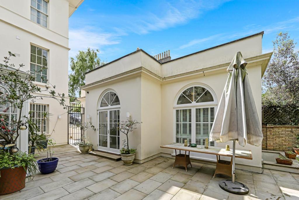 a patio with a bench and an umbrella at LONDON ONE BED ANNEX in London