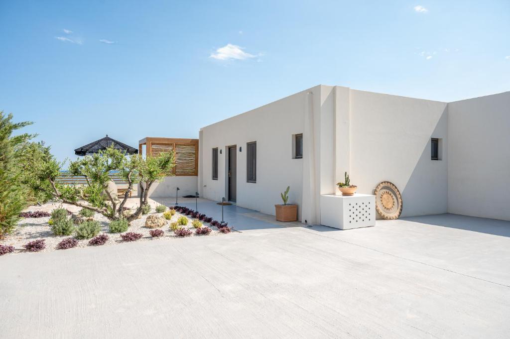 a white house with a courtyard with plants at Mnḗmē Suites & Villas in Kastrí