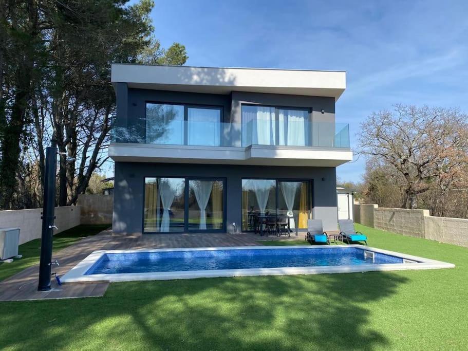 uma casa com uma piscina em frente em Villa Sara em Juršići