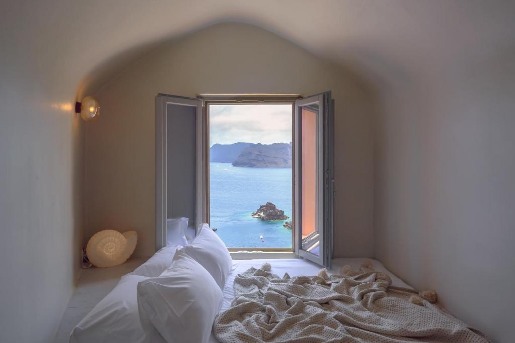 Oia Waves by SV في أويا: غرفة نوم مع نافذة كبيرة تطل على الماء