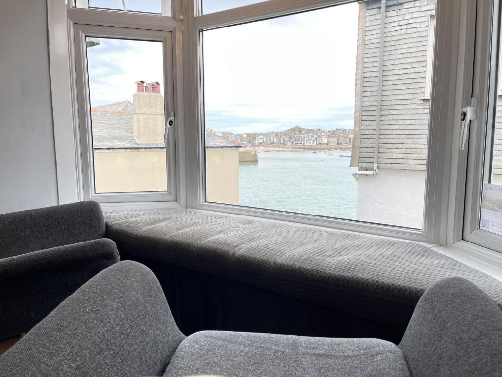 a living room with two chairs and a large window at 10 The Warren, amazing seaviews from every floor! in St Ives