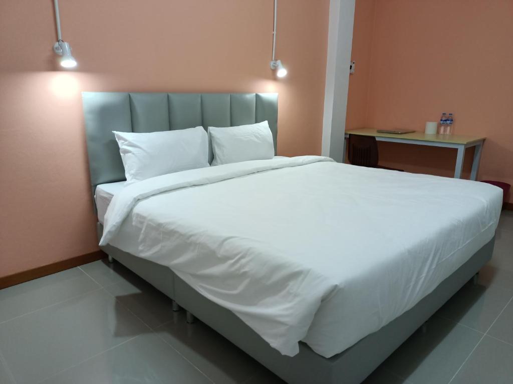 um quarto com uma cama grande com lençóis brancos e almofadas em โรงแรม เดอะพีช / The Peach hotel em Phetchaburi
