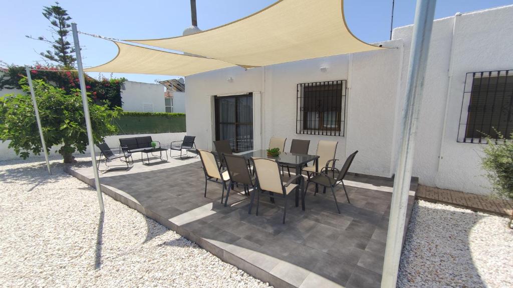 un patio con mesa y sillas bajo una sombrilla amarilla en Chalet "El Paraíso del Cabo", en Retamar