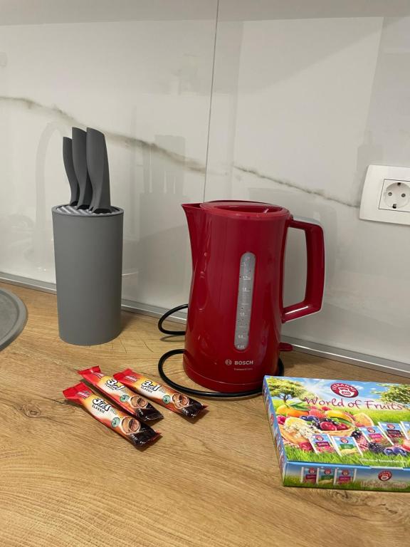 a red pitcher and utensils and a box of candy at Apartman Stela in Knin