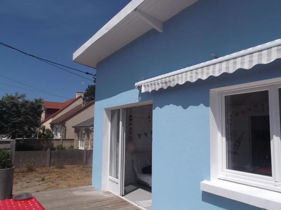 una casa azul con puerta y ventana en C'est une maison bleue, juste à côté de la plage..., en Barneville-Carteret