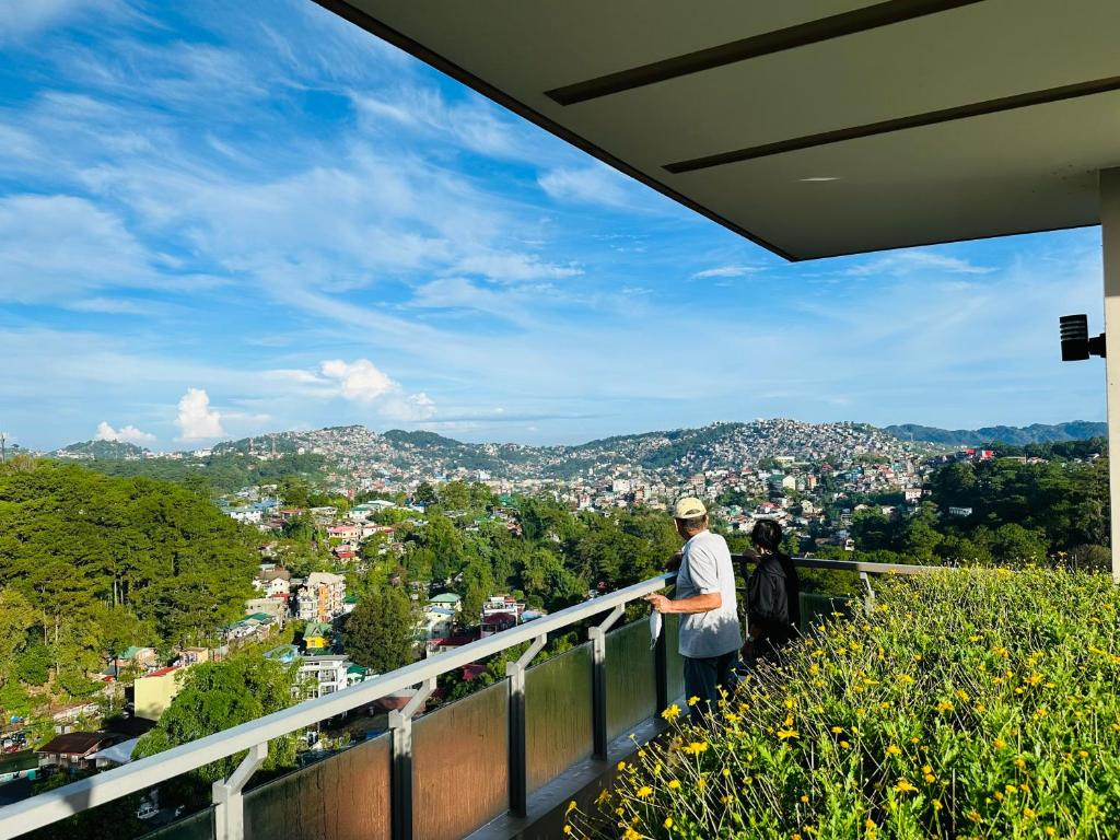 a man standing on a balcony looking at a city at Condo Suite Near JohnHay MinesView TheMansion in Baguio