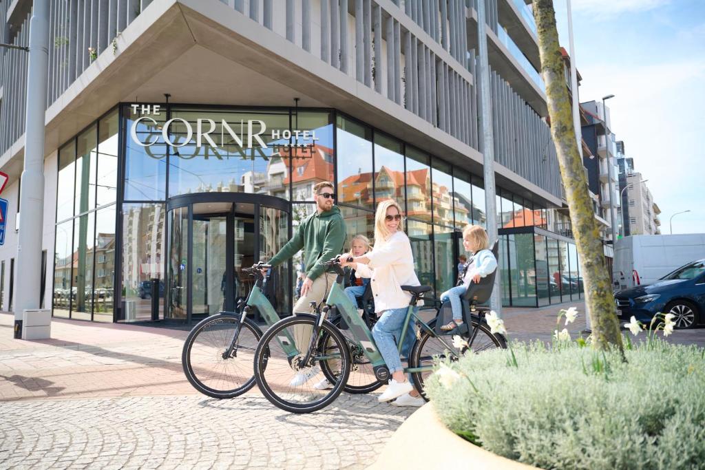 eine Familie auf Fahrrädern vor einem Geschäft in der Unterkunft The CORNR Hotel in Nieuwpoort
