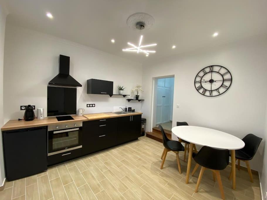 eine Küche mit einem Tisch und einer Uhr an der Wand in der Unterkunft Au coeur de Brantôme : superbe appartement in Brantôme