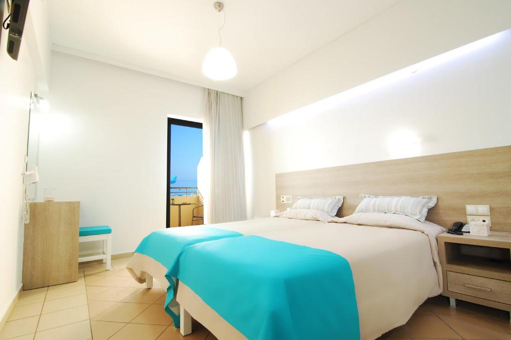 a bedroom with a large bed with a blue blanket at Medusa Apartments in Rethymno