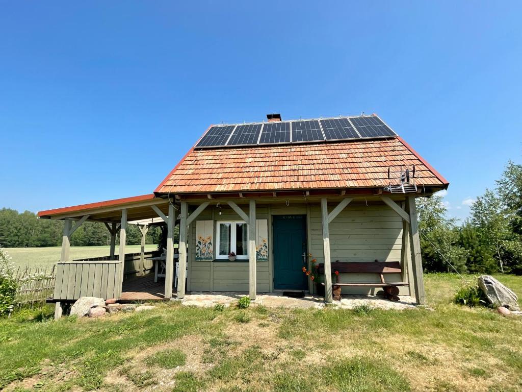 una pequeña casa con paneles solares en el techo en POLNA CHATA, en Jasionówka