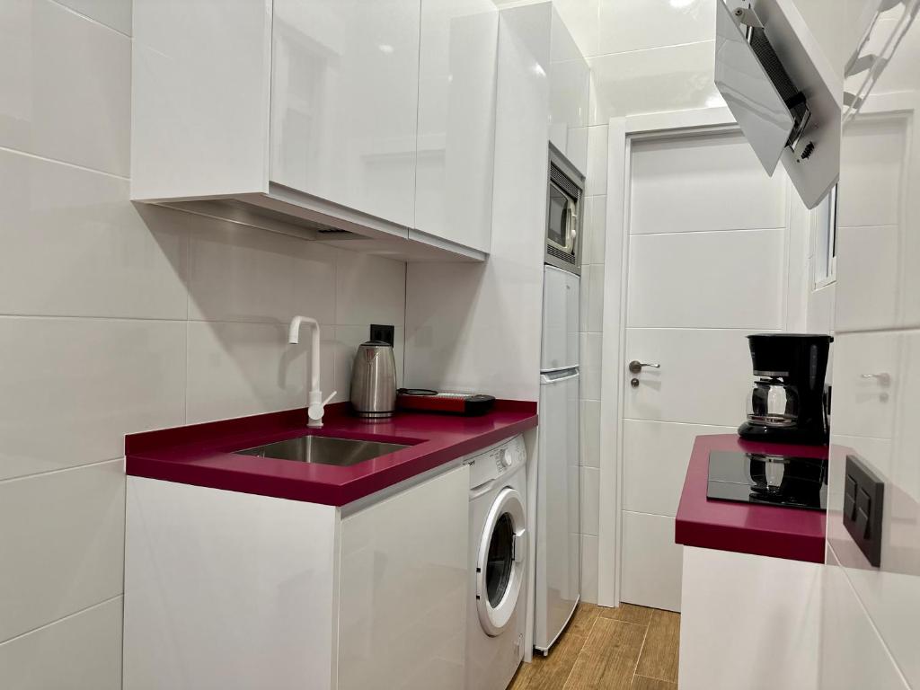 a kitchen with a sink and a washing machine at Love Pink Gran Via in Madrid