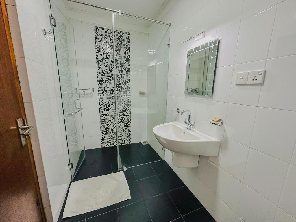 a white bathroom with a sink and a shower at Grace in Nuwara Eliya