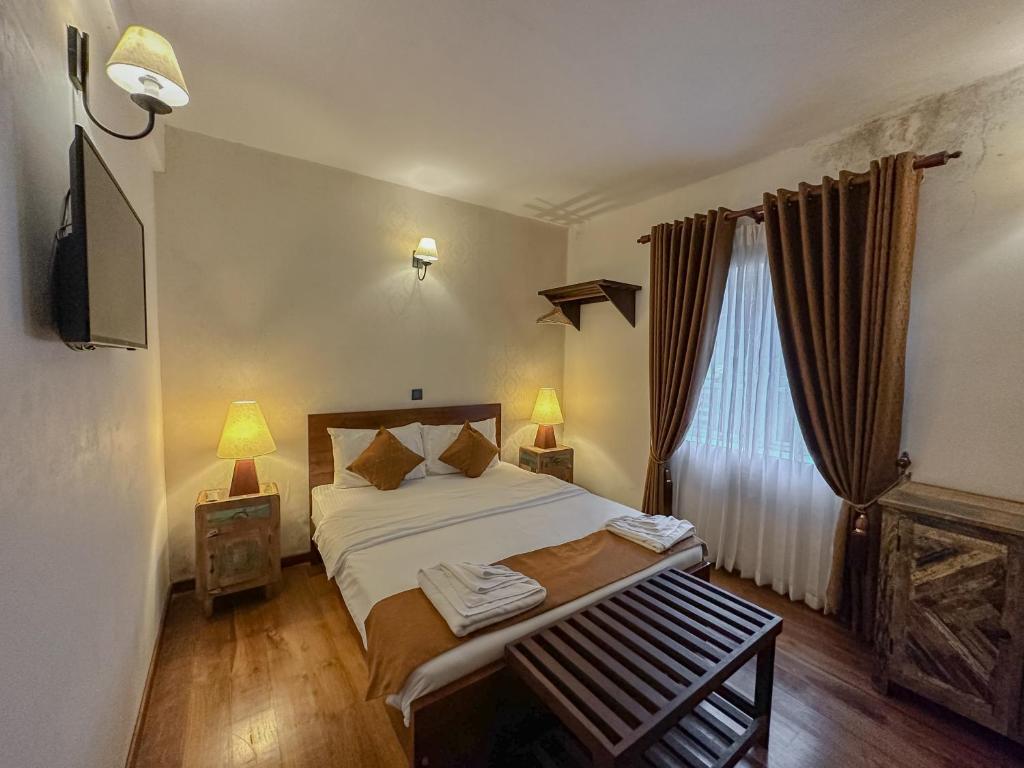 a bedroom with a bed and two lamps and a television at Grace in Nuwara Eliya