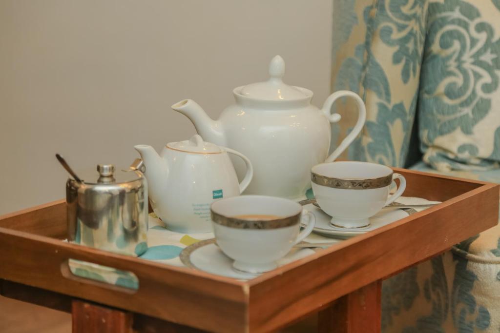 a wooden tray with three cups and a tea set at Grace in Nuwara Eliya