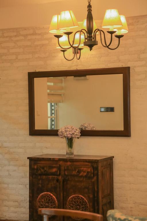 a mirror with a vase of flowers on a dresser at Grace in Nuwara Eliya
