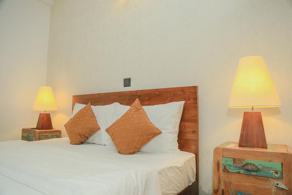 a bedroom with a bed with pillows and two lamps at Grace in Nuwara Eliya