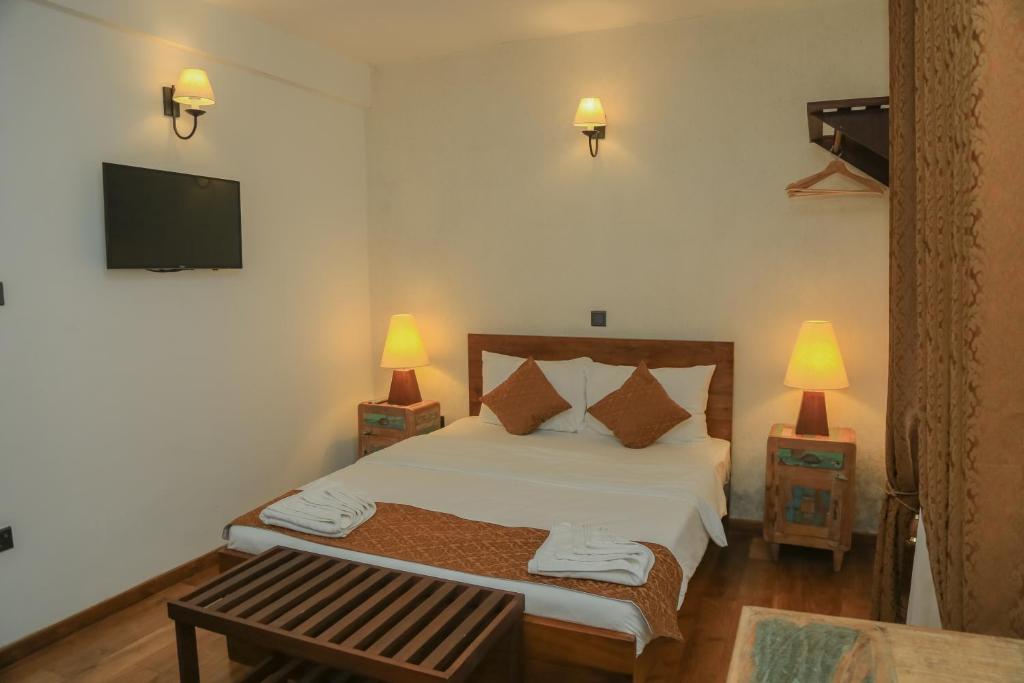 a bedroom with a bed with two lamps and a tv at Grace in Nuwara Eliya