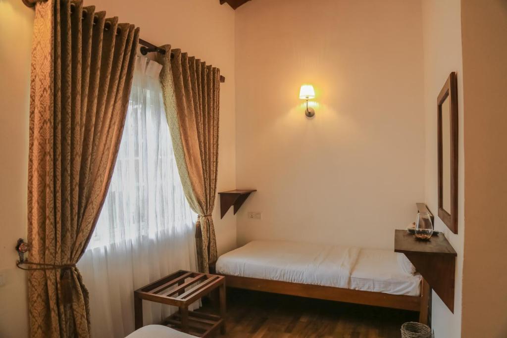 a small bedroom with a bed and a window at Grace in Nuwara Eliya