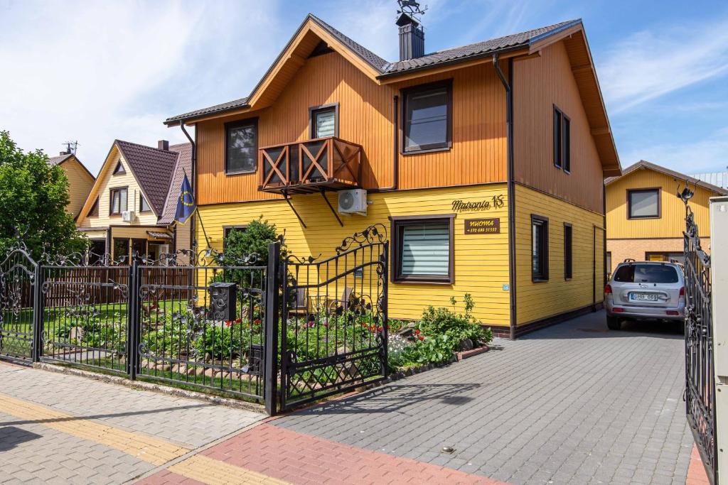 a yellow house with a fence in front of it at Vila Dalija in Palanga