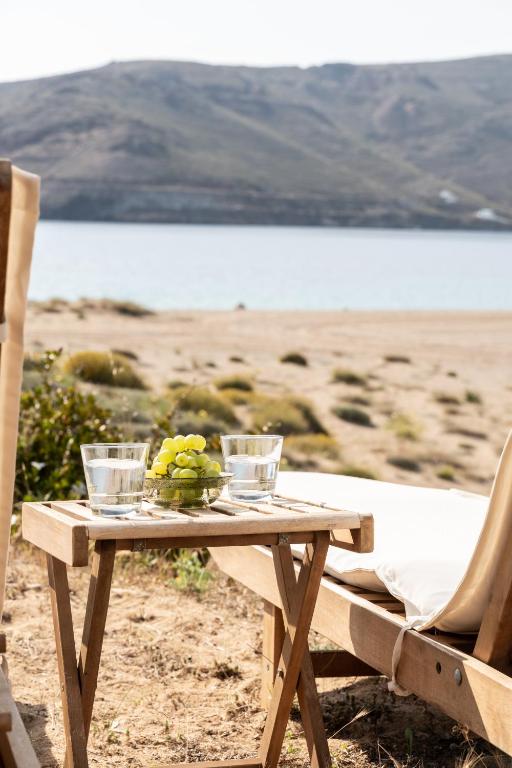 a wooden table with a bowl of fruit on a beach at Ammoa Beach Residences in Vayiá