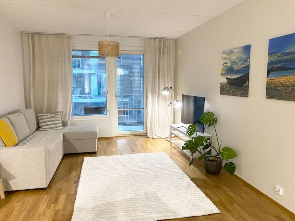 uma sala de estar com um sofá branco e uma televisão em JATKASAARI-1 Dream stay on Helsinki seafront em Helsinque