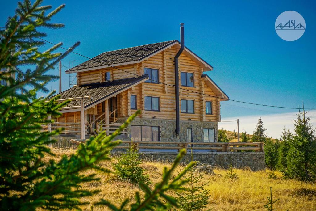 ein großes Holzhaus inmitten eines Feldes in der Unterkunft Cabana Alaska in Ranca