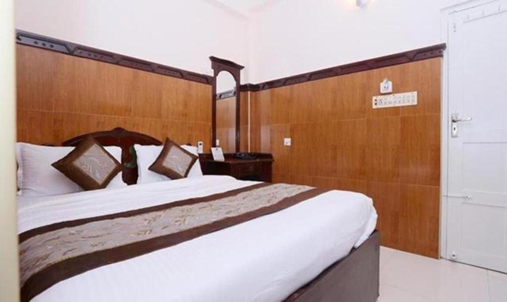 une chambre avec un grand lit avec une tête de lit en bois dans l'établissement Ascot Hotel, à Cochin