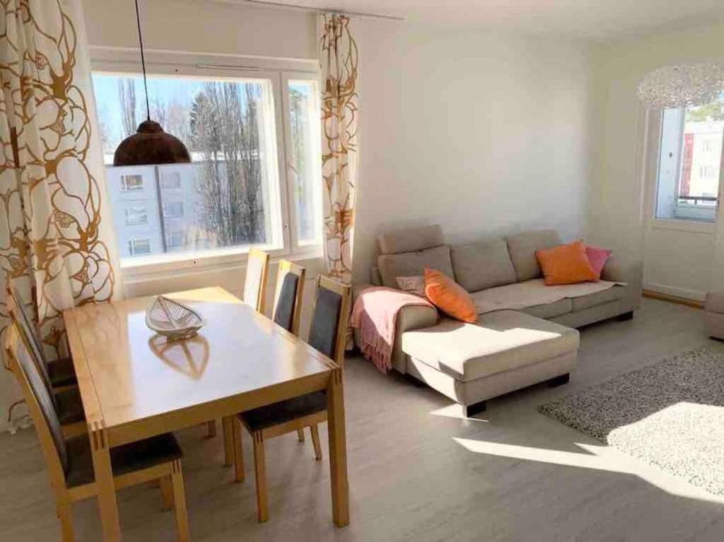 un soggiorno con divano e tavolo di MELLUNMAKI Renovated 3 bedroom apt next to metro a Helsinki