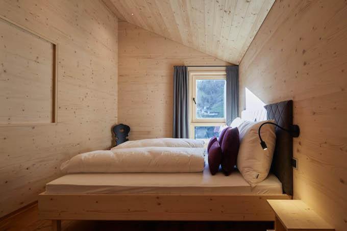 een bed in een houten kamer met een raam bij Haus Motta in Gaschurn