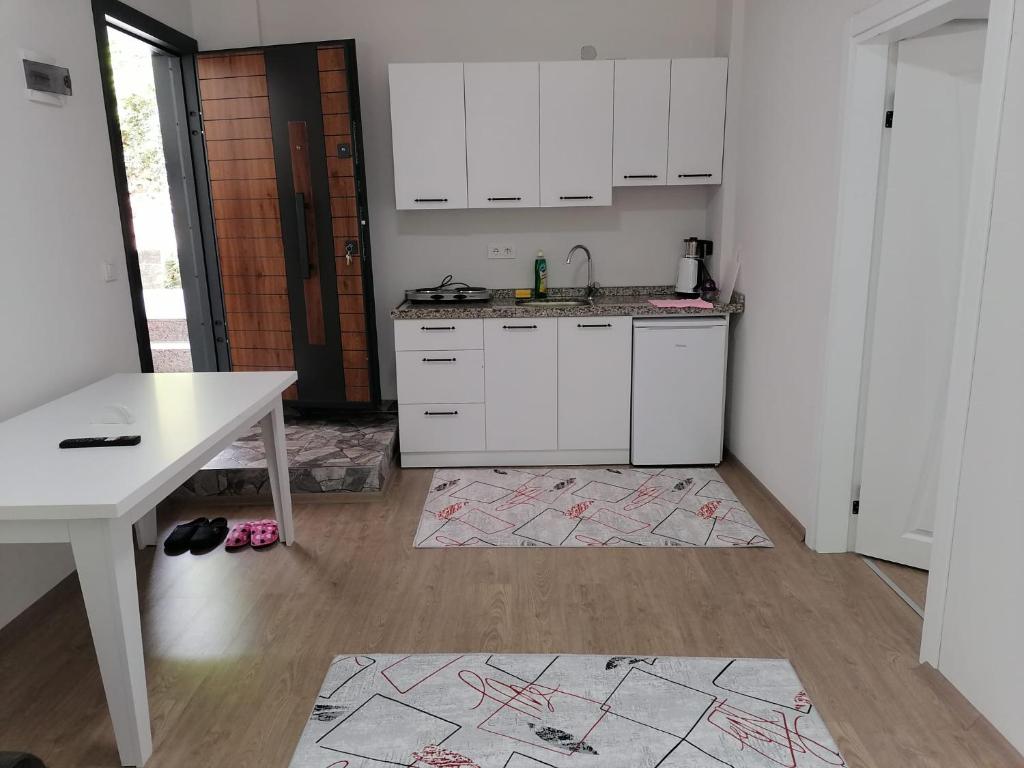 a kitchen with white cabinets and a white table at Erme Apart Evler in Dernekpazarı