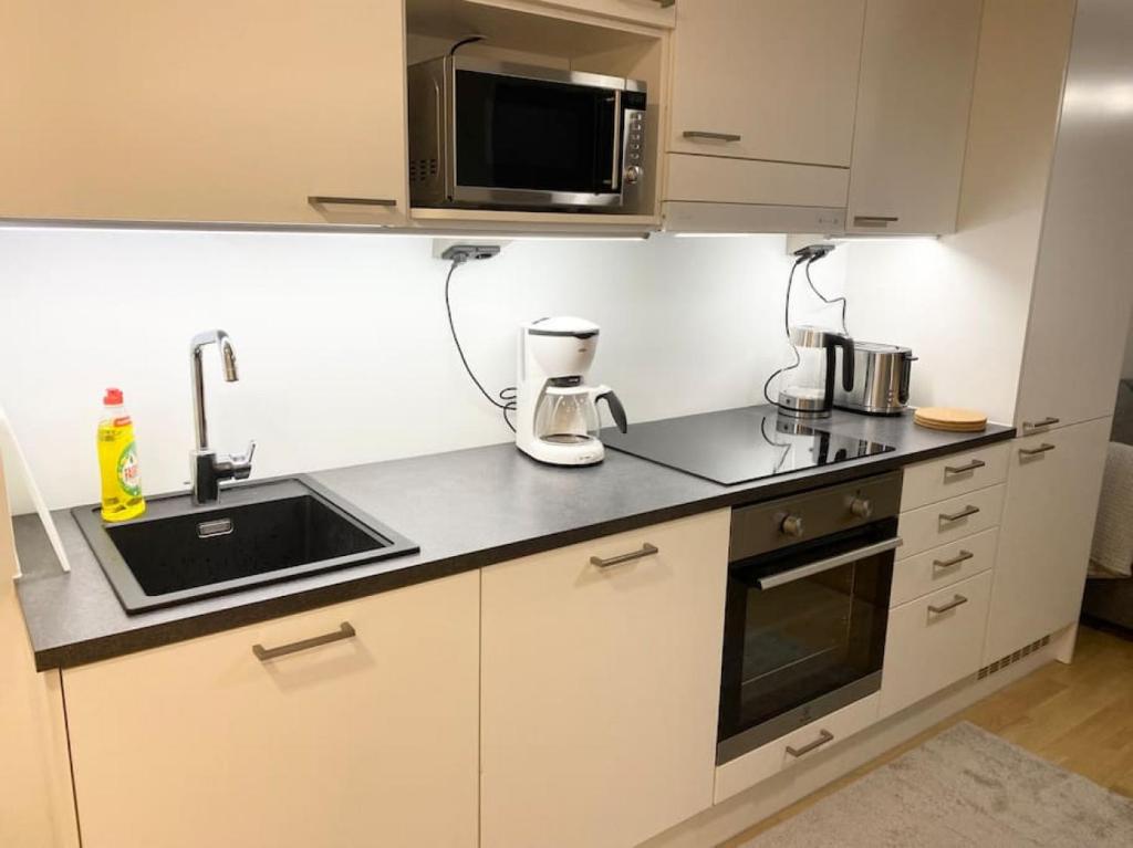 a small kitchen with a sink and a microwave at PEURANIITTY-2 Modern well equipped apartment in Espoo