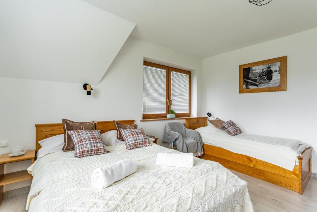 two beds in a room with white walls at Noclegi Siuster - komfortowe pokoje z widokiem na góry - doskonała lokalizacja, niedaleko Term Bukovina in Bukowina Tatrzańska