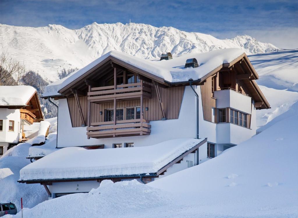 a house covered in snow with mountains in the background at Appartement Montanea in Schruns-Tschagguns