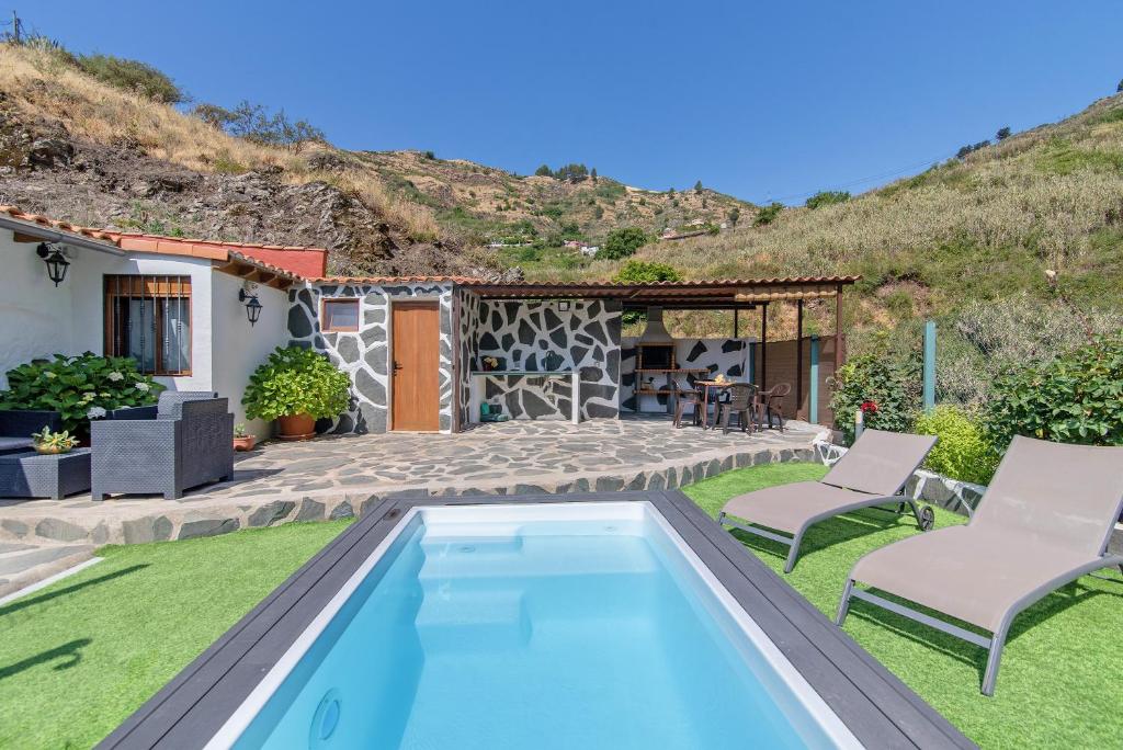 basen w ogrodzie z dwoma krzesłami i dom w obiekcie Casa Abuela Fela w mieście Vega de San Mateo
